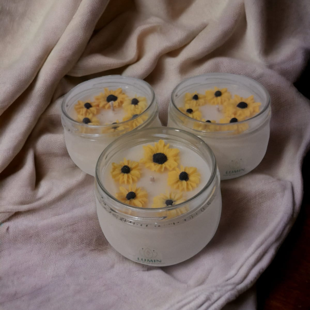 La vela de soja Girasol de la marca Lumin es el complemento perfecto para crear un ambiente acogedor y relajante. Fabricada con cera de soya, su diseño de girasoles en color blanco le da un toque elegante y natural. Ideal para dar un toque de luz y frescura a cualquier espacio. Tamaño mediano.